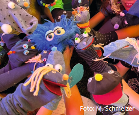 Das Bild zeigt verschiedene bunte Handpuppen, die aus Socken hergestellt wurden